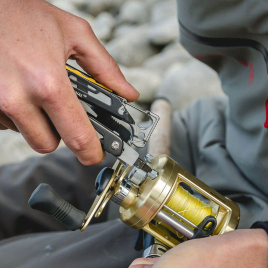 Translation missing: en.A person using a Black & Stainless Leatherman Signal® multitool to fix a fishing reel
