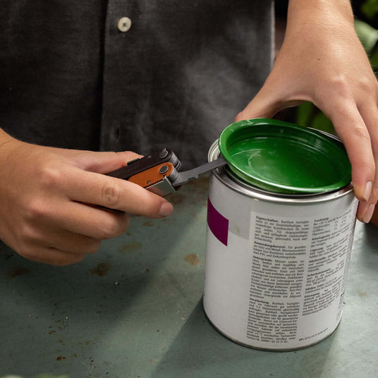 Translation missing: es.Person using a Burnt Sienna Leatherman Rebar® to open a paint can with a green lid
