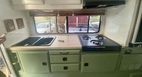 Translation missing: es.Modern camper kitchen with double sink, gas stove, and ample storage, featuring a bright and spacious layout with a Stainless Steel Leatherman Skeletool® on top