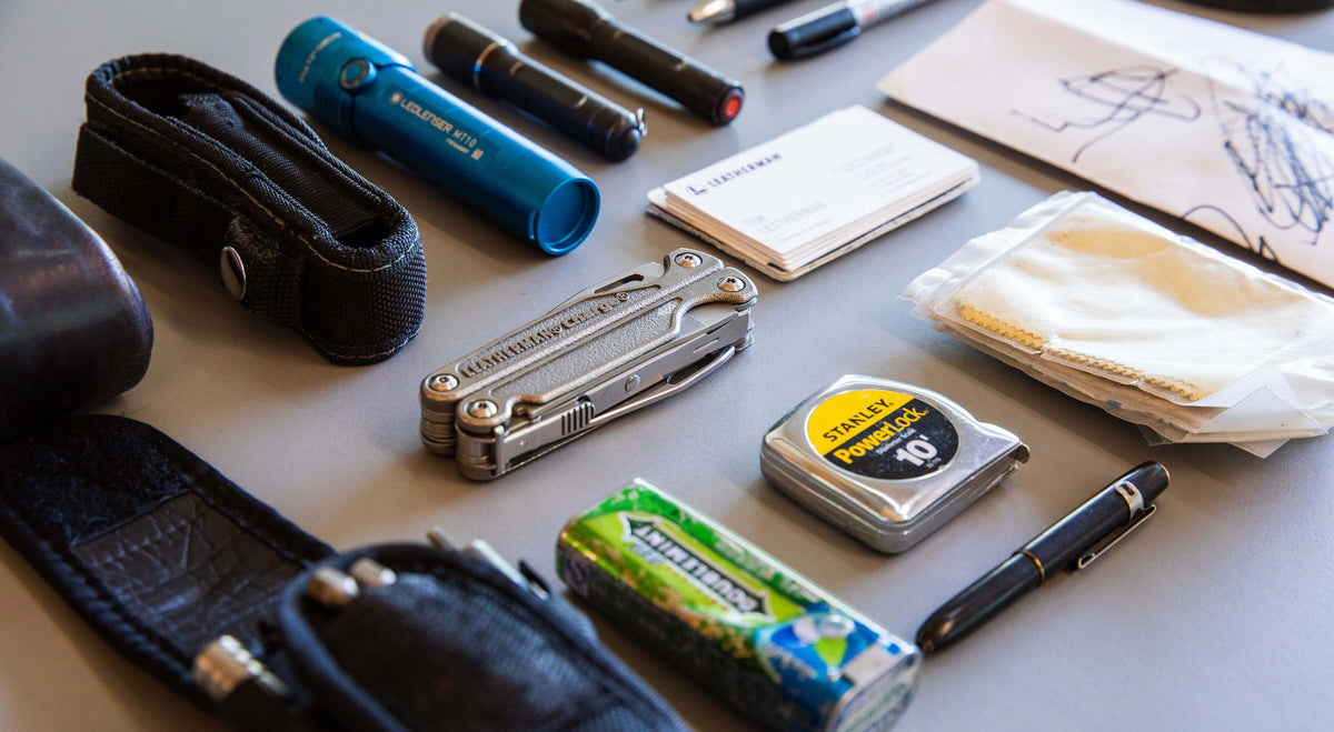 Stainless Steel Leatherman Charge® multi-tool with other everyday items on a table.