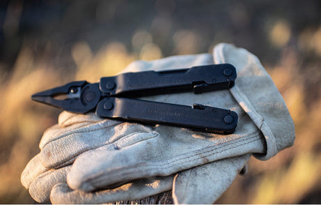 Translation missing: en.Black Super Tool® 300 multi-tool resting on a leather gloves outdoors, showcasing rugged utility and versatility