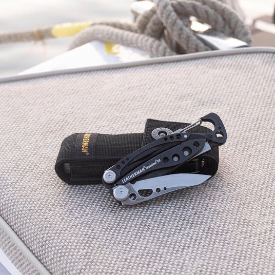 Translation missing: en.Black &amp; stainless Leatherman Skeletool® CX with nylon sheath on a textured surface