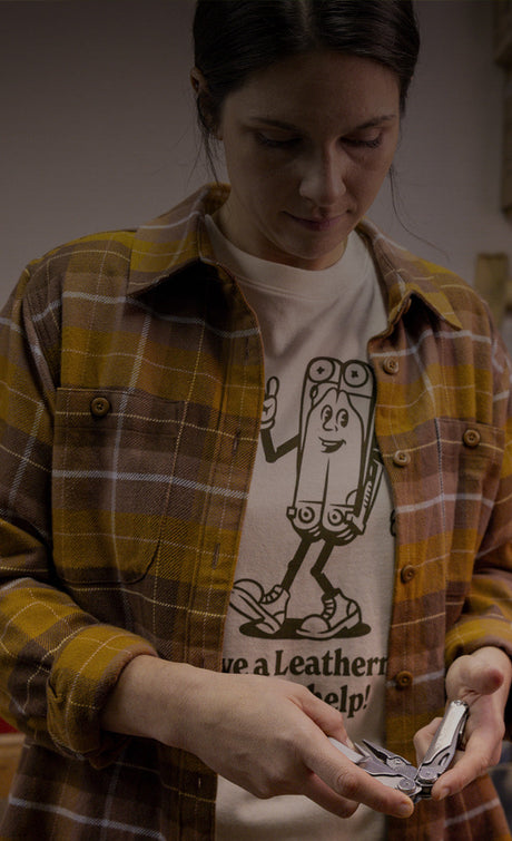 Translation missing: en.Woman wearing a Leatherman Mr. Wave tee in Natural Raw color with a plaid button up shirt on top holding a stainless steel Leatherman multi-tool