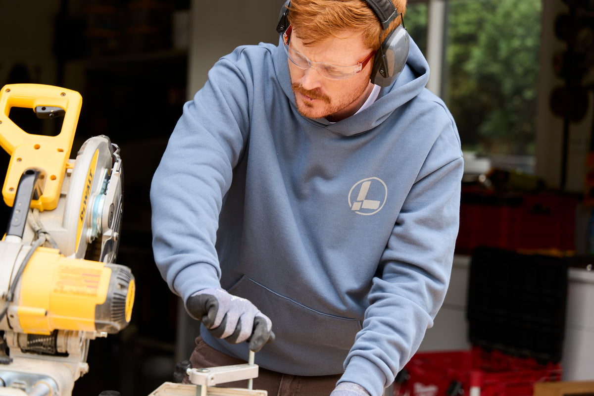 Translation missing: en.A person wearing a storm blue Leatherman Classic Hoodie operating a saw while working on a woodworking project