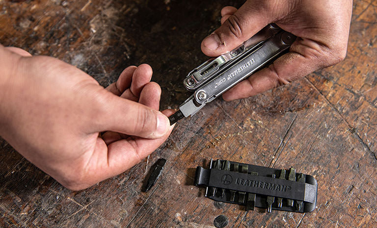 Translation missing: en.Man replacing a bit from Leatherman Bit Kit on Leatherman Curl over wood table