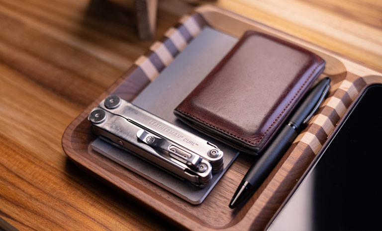 Translation missing: en.Leatherman Curl, dark brown leather wallet and black pen on top gray notepad nicely arrange on wooden tray