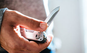 Translation missing: en.Man in gray sweatshirt opening knife blade on Leatherman T4