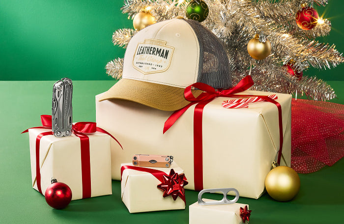 Translation missing: en.Natural/Gold PNW trucker hat and multi-tools beside holiday gifts under a Christmas tree with ornaments