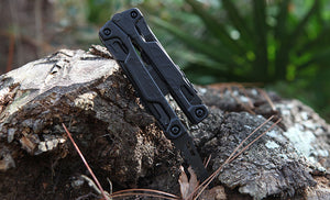 Translation missing: en.Black Leatherman OHT saw blade inside a piece of wood outdoors