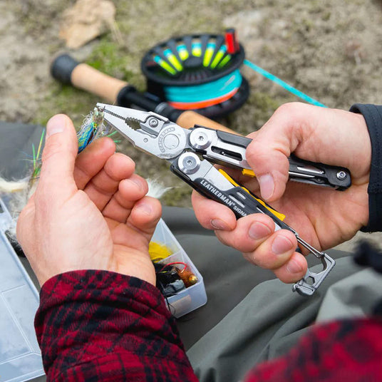 Translation missing: en.Person using a Black &amp; Stainless Leatherman Signal® pliers to adjust a fishing hook
