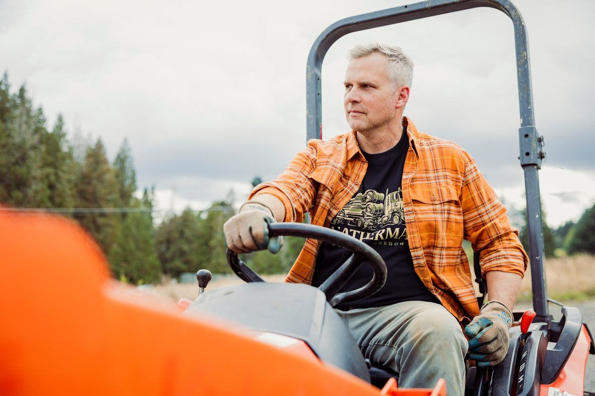 Translation missing: es.A person wearing a black Leatherman Timber Tee driving a tractor outdoors