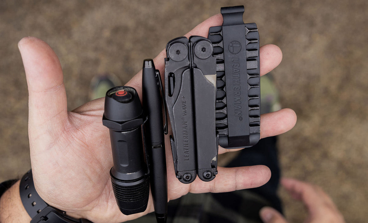 Translation missing: en.Hands showcasing a Black Leatherman Wave® Plus, bit kit, pen, and flashlight